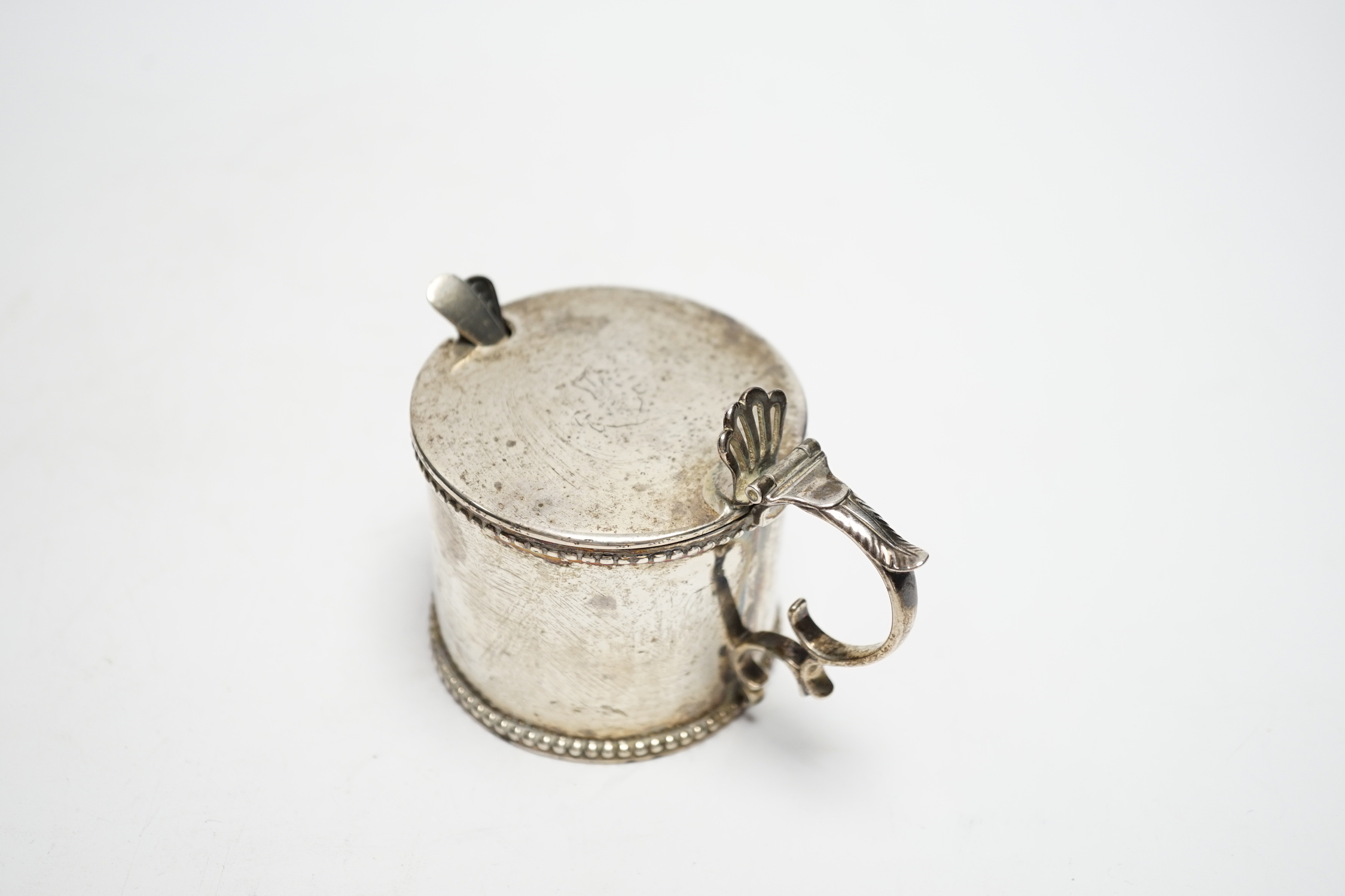 An early Victorian silver drum mustard, maker's mark rubbed, Birmingham, 1843, height 75mm, with two associated spoons, one silver.